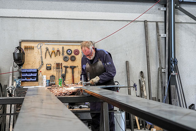 Werknemer van Steellife stalen producten aan het slijpen