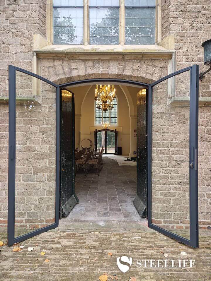 Stalen getoogde buitendeuren in kerkgebouw
