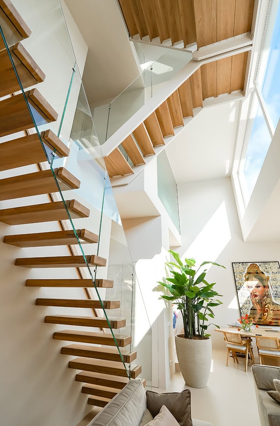 Moderne interieurtrap met houten treden en glazen balustrade in een lichte woning.
